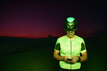 Image showing A triathlete using a smartphone while taking a break from a hard night's cycling training