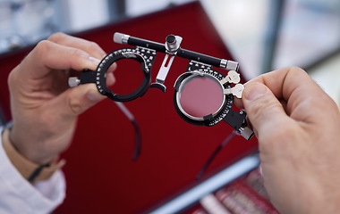 Image showing Optometry, healthcare and optometrist with trial lens for a eye test in a optical clinic. Vision, eyecare and hands with a prescription optic instrument or glasses for a exam in a ophthalmology store
