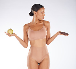 Image showing Black woman, studio and choice for chocolate, apple and health for weight loss, body or nutrition by background. Gen z model, underwear or decision for diet, fruit or candy for thinking of cheat day