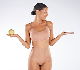 Image showing Black woman, fitness and body with an apple, chocolate and smile for balance, wellness and grey studio background. Mockup, African American female and lady with fruit, candy bar and diet on backdrop