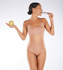 Image showing Apple, body and woman eating chocolate in a studio for a sweet snack, candy or craving. Health, wellness and female model enjoying cocoa treat while holding fruit for balance diet by gray background.