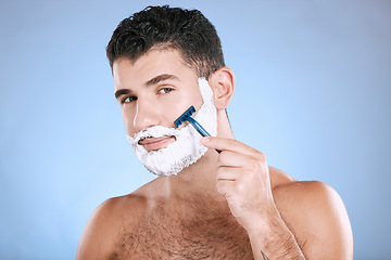 Image showing Shaving, grooming and portrait of a man with cream for beard isolated on a blue background. Skincare, beauty and model with razor to shave hair on face with foam for a clean facial look on a backdrop