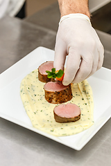 Image showing Chef garnishing meat plate
