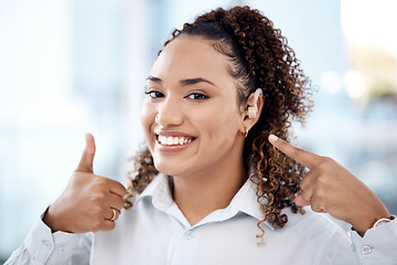 Image showing Thumbs up, happy and portrait of a woman with a hearing aid pointing to her ear in the office. Happiness, success and young professional female with a deaf piece and a approval gesture in workplace.