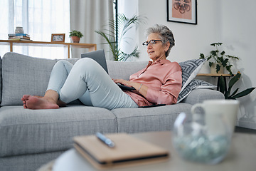 Image showing Senior woman, laptop and relax on sofa in the living room checking email, typing or writing at home. Elderly female freelancer or writer relaxing on lounge couch working or reading on computer