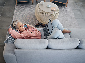 Image showing Laptop, phone call and senior woman on a sofa with a remote job working on a project at her home. Happy, laugh and elderly female on a mobile conversation while on a computer in her living room.