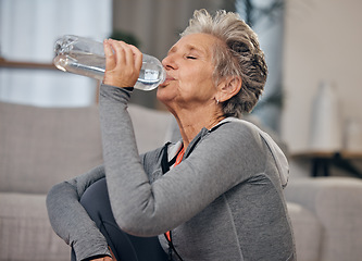 Image showing Drinking, water and fitness with a senior woman in her home for wellness, hydration or retirement. Exercise, drink or thirsty with a mature female training in a house during a workout to stay active