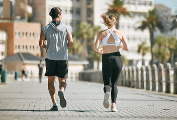 Image showing Fitness, teamwork or coaching with a runner couple on the promenade for cardio or endurance from the back. Exercise, wellness or workout with a man and woman athlete running outdoor in the city