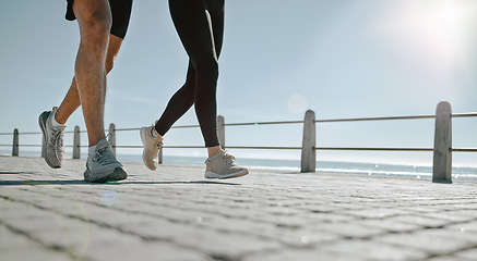 Image showing People, legs and running at the beach for exercise, cardio workout or training together outdoors. Leg of friends taking run, walk or jog on warm sunny day by the ocean coast for healthy wellness