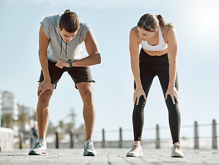 Image showing Running, tired couple and watch for time, performance and goals on blue sky for wellness. Man and woman outdoor in nature for workout, fitness and exercise for healthy lifestyle and body fatigue