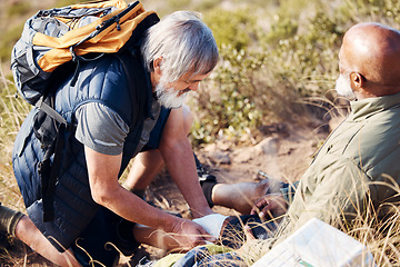 Image showing First aid, leg injury and hiking with old men in nature for trekking, adventure and fitness. Help, bandage and medical with friends and knee pain on trail for backpacking, discovery and emergency