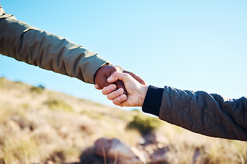 Image showing Friendship, help and men holding hands on a hike for support while climbing a rock on a mountain. Assistance, adventure and interracial male friends trekking together for fitness challenge in nature.