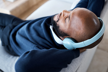 Image showing Music top view, headphones and black man on sofa in home living room streaming audio. Meditation, relax technology and male on couch in lounge listening to peaceful podcast, radio or sound in house.