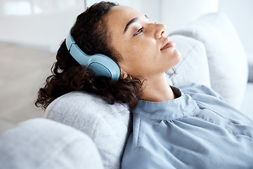 Image showing Black woman, headphones and relax on sofa with music, audio streaming and peace with smile in lounge. Young lady, sound technology and listening to radio, podcast and thinking on living room couch