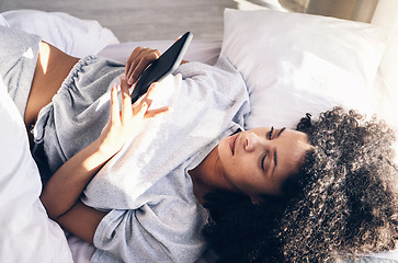 Image showing Black woman, bed and phone in home bedroom for social media, texting or internet browsing in the morning. Technology, relax and female with mobile smartphone for web scrolling or networking in house.