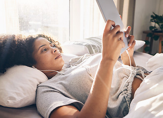 Image showing Music earphones, black woman and tablet in bed in bedroom for social media, texting or internet browsing in the morning. Technology, relax and female with touchscreen for streaming podcast or radio.