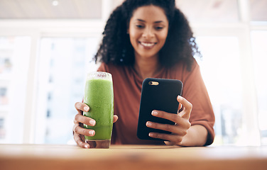 Image showing Hands, smoothie and smartphone with a black woman in the kitchen of her home for health, weight loss or nutrition. Mobile, glass and wellness with a female posting a status update on social media