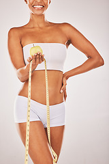 Image showing Lose weight, tape measure and body with black woman and apple for nutrition and diet with fitness isolated on studio background. Health, smile and healthy lifestyle with weightloss and clean eating