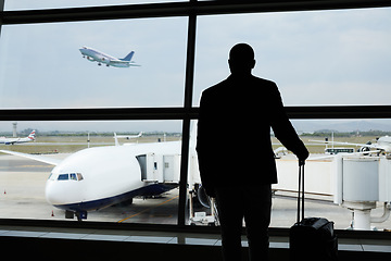 Image showing Airport, travel and silhouette business man watch plane fly, flight booking or transportation for world trip. Suitcase luggage, airport departure and back of person on holiday, vacation or journey