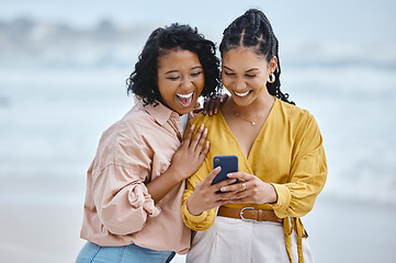 Image showing Phone, beach and meme with black woman friends laughing together by the ocean or sea in the morning. Nature, joke or social media with a young female and friend reading a funny text on the coast