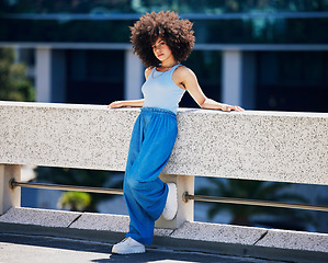 Image showing Portrait, fashion and serious with a black woman in the city on a bridge, looking relaxed during summer. Street, style or urban and an attractive young female posing outside with an afro hairstyle