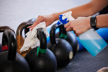 Image showing Gym, hygiene and hands cleaning kettlebell with cloth and spray bottle, dirt and germs at fitness studio. Janitor, cleaner or caretaker at sports club washing dust and bacteria from workout equipment