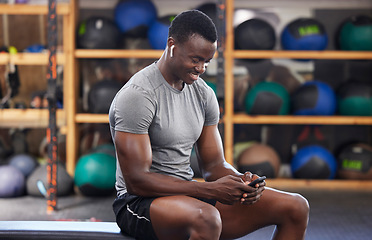 Image showing Phone, fitness and black man in gym training, workout or exercise social media or internet search for health tips. Bodybuilder, sports person listening to music or typing on smartphone chat or mobile