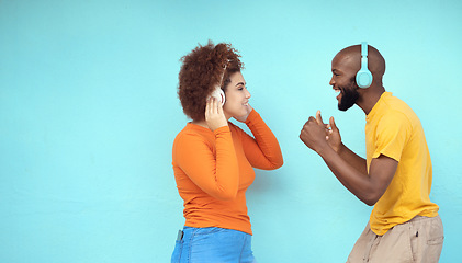 Image showing Couple of friends in headphones isolated on a blue background for dancing, celebration and listening to music. Black woman with dance partner or people with audio, podcast and gen z technology mockup