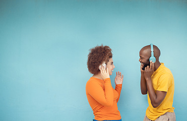 Image showing Couple of friends listening to music isolated on a blue background with headphones for gen z mockup space. Black woman with happy partner or people with audio, podcast and youth technology mock up