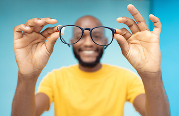 Image showing Hands, glasses and vision with a black man in studio on a blue background for prescription frame lenses. Spectacles, eyesight and eyewear with a male indoor to promote new round frames for seeing