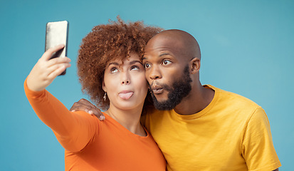 Image showing Couple, hug and funny faces selfie on blue background, isolated mockup or wall mock up for social media. Comic, goofy and silly black man and woman on photography tech for interracial profile picture