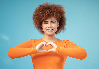 Image showing Heart, hand and portrait of woman in studio for love, happy and smile against blue background space. Emoji, hands and face of girl model relax with finger, frame and loving message, gesture and sign