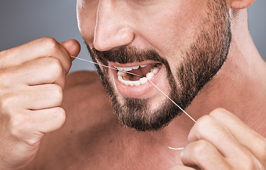 Image showing Mouth floss, tooth and man in studio for beauty, healthy body care and hygiene on background. Closeup of male, teeth flossing and cleaning face for facial wellness, fresh breath and dental cosmetics