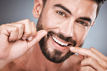 Image showing Floss, cleaning teeth and portrait of man in studio for beauty, healthy body and hygiene on background. Male model, tooth flossing and mouth for facial smile, fresh breath and happy dental wellness