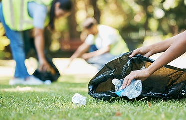 Image showing Volunteer hands, cleaning up and trash bag for pollution, carbon footprint and eco friendly in park. Closeup, zoom and plastic collection outdoor, sustainability and charity service for environment