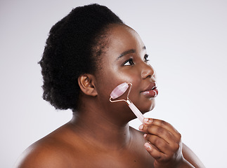 Image showing Skincare, face and massage with a model black woman in studio on a gray background using a roller. Facial, luxury and beauty with a young plus size female indoor to promote an antiaging product