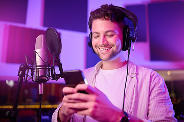 Image showing Man, phone and smile in music studio chatting, social media or podcast post at the workplace. Happy male auto tuner smiling on smartphone for networking, sound track or listening in sound proof room