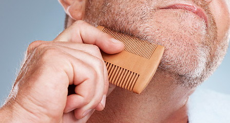 Image showing Grooming, hair care and man brush beard for wellness, healthy skin and hygiene on blue background. Salon aesthetic, cleaning and face zoom of male with barber comb for facial, skincare and beauty