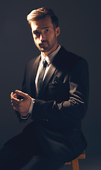 Image showing Gentleman, fashion and portrait of a man in suit with style for business looking serious in a studio black background. Confident, proud and handsome male model sitting on a chair adjusting sleeves