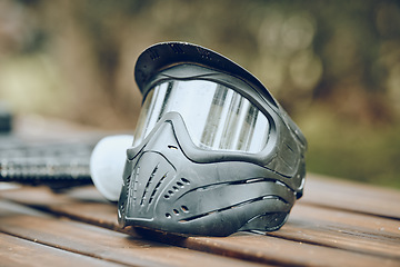 Image showing Helmet, paintball and sports with equipment on a table outdoor for military or army training on a battlefield. Safety, exercise and mask with combat accessories on a wooden surface for war simulation