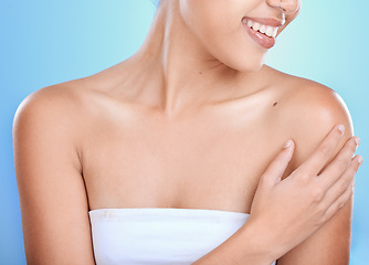 Image showing Woman, hands and smile for skincare, cosmetics or spa treatment against a blue studio background. Hand of happy female touching shoulder and smiling in beauty for soft smooth skin, self love or care