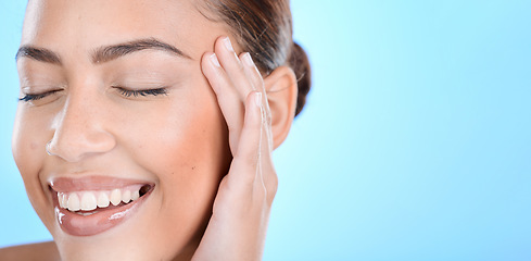 Image showing Woman, skincare and hands on face in studio for makeup, wellness or gentle cleaning on blue background. Face, beauty and girl skin model relax in luxury, facial and cosmetic treatment while isolated