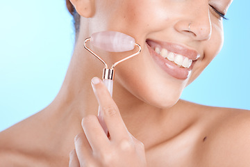 Image showing Skincare, massage and woman with face roller in studio for beauty, wellness and anti aging treatment on blue background, Facial, happy and girl model relax with rose quartz product and isolated