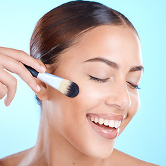 Image showing Brush, cosmetics smile and woman face with cosmetic and happiness in a studio. Blue background, isolated and young person with eyes closed feeling calm from skincare and makeup artist beauty