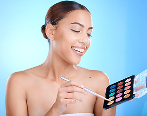 Image showing Makeup, palette and woman isolated on blue background for youth, beauty or skincare product promotion. Model, artist or creative person, cosmetics eyeshadow and color choice for face in studio mockup