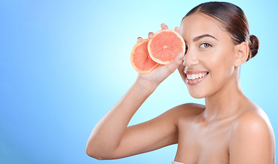 Image showing Skincare, portrait and woman with grapefruit in studio for cosmetics, wellness and treatment on blue background. Face, beauty and girl model on fruit, product and luxury cleaning, grooming or hygiene