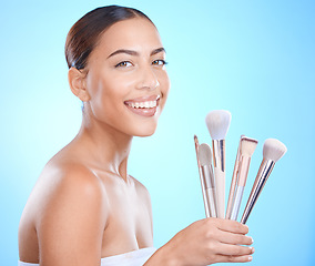 Image showing Cosmetic, makeup brushes and portrait of a woman in a studio for a beauty, natural and face routine. Cosmetics, skincare and female model from Brazil with a facial glow isolated by a blue background.