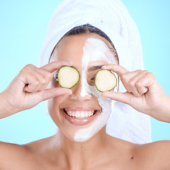 Image showing Beauty, cucumber and skincare face mask on a woman with vegetable slice for dermatology cosmetics. Aesthetic model person with spa facial for self care, skin glow and wellness on blue background
