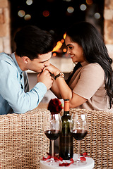 Image showing Young couple on a date, romantic restaurant evening and kiss on the hand at cafe fireplace with wine glasses. Happy people in love, valentines day together and girlfriend smile at handsome boyfriend