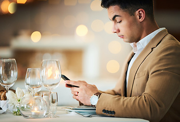 Image showing Man, texting and phone at restaurant table for food, night and waiting for valentines day date. Young male, smartphone and wine glass for fine dining, bottle service or drink at dinner celebration